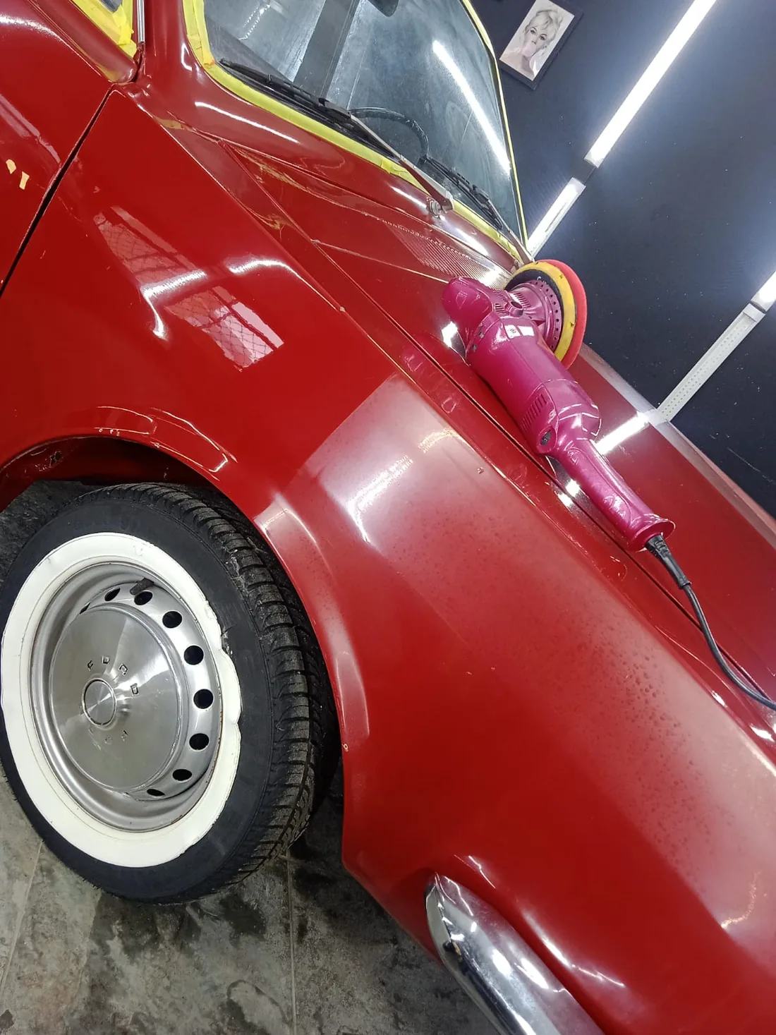 Politriz e reflexos na pintura de um carro clássico vermelho